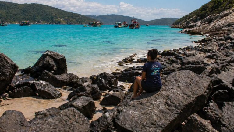 Guia de turismo observando o mar em Arraial do Cabo com barcos e água cristalina