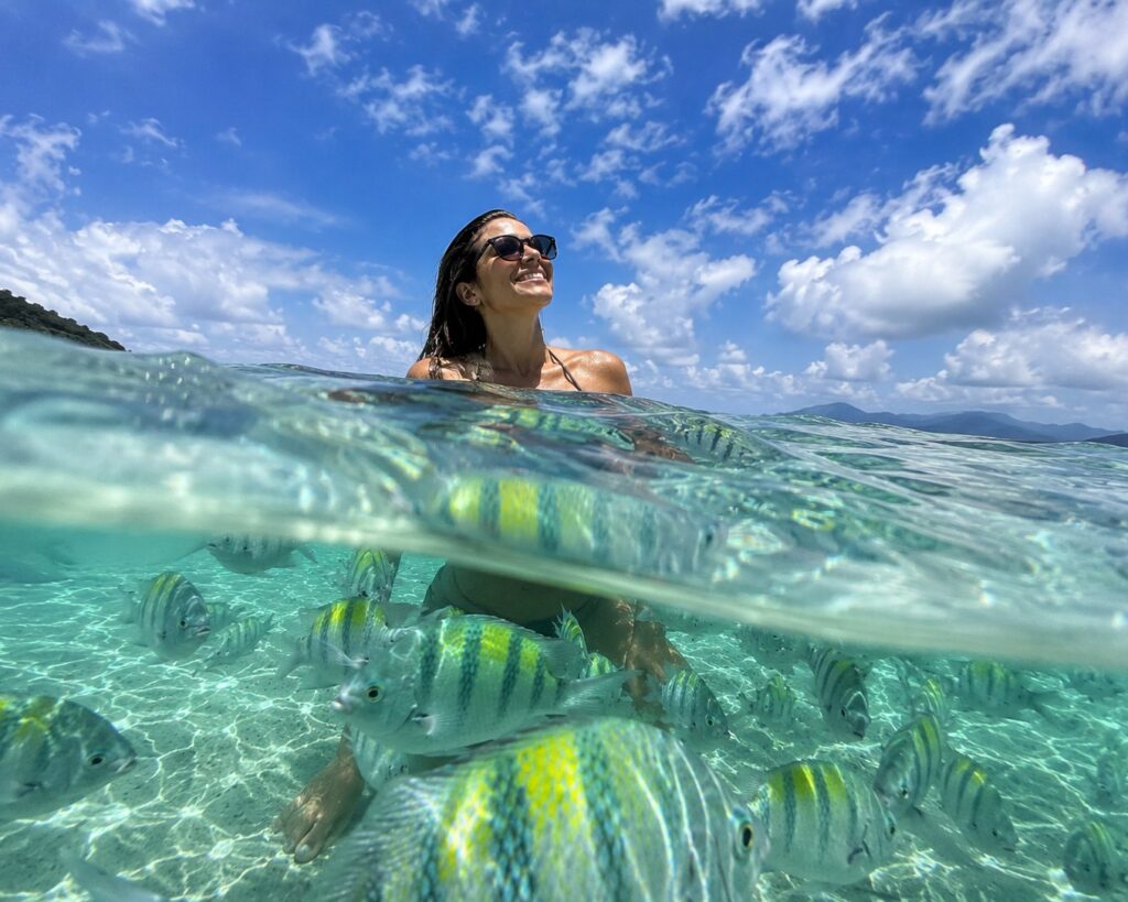 Turista mergulhando na Lagoa Azul durante a excursão para Angra dos Reis saindo do Rio de Janeiro, cercada por águas cristalinas e peixes na Costa Verde.