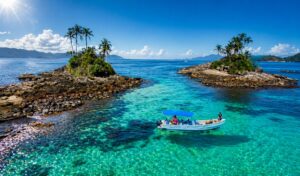 Vista aérea das Ilhas Botinas em Ilha Grande, com águas cristalinas em tons de azul-turquesa e embarcação durante passeio de lancha.